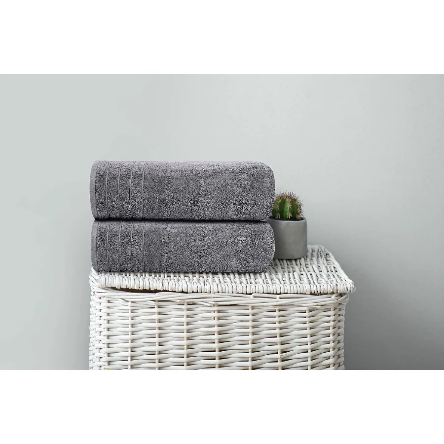 Dark grey bath towels stacked in a woven basket