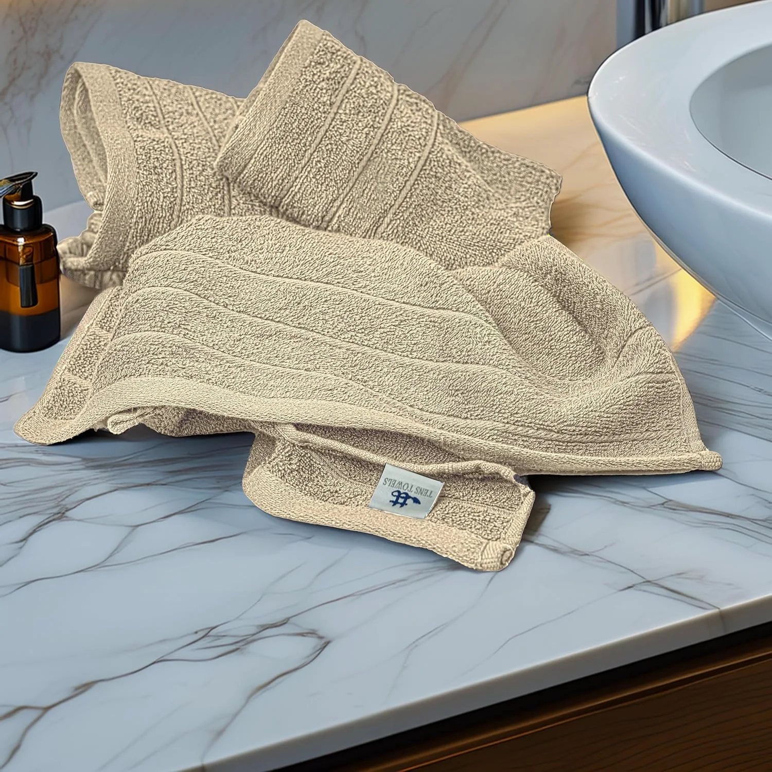 Beige hand towels draped on a marble counter